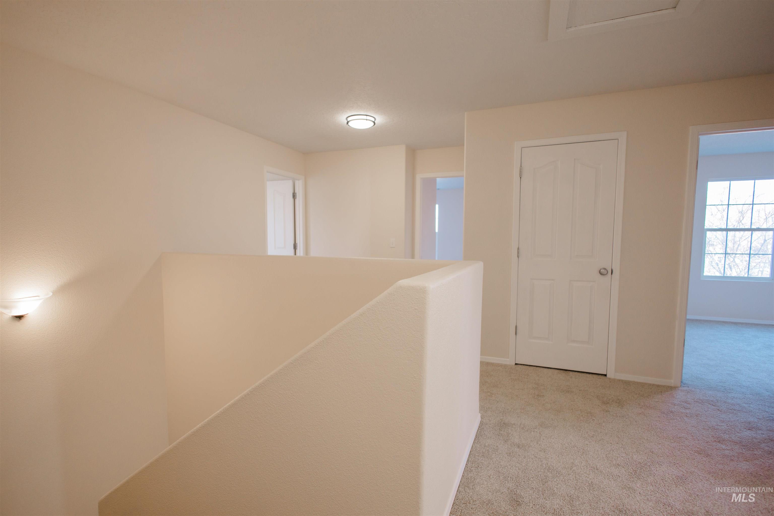 Corridor featuring light colored carpet and an upstairs landing
