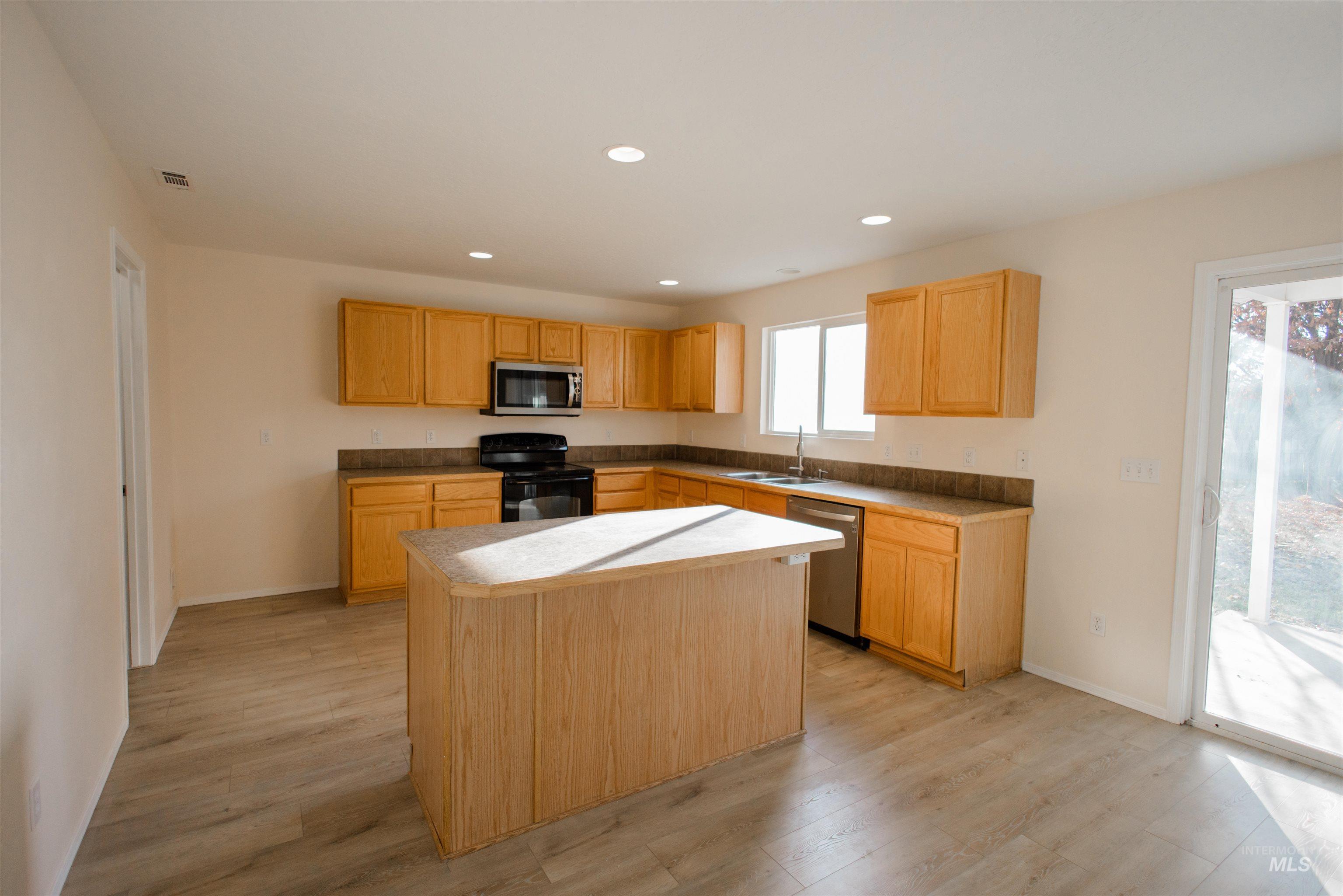 Kitchen featuring stainless steel appliances, light countertops, light wood-style floors, recessed lighting, and a center island
