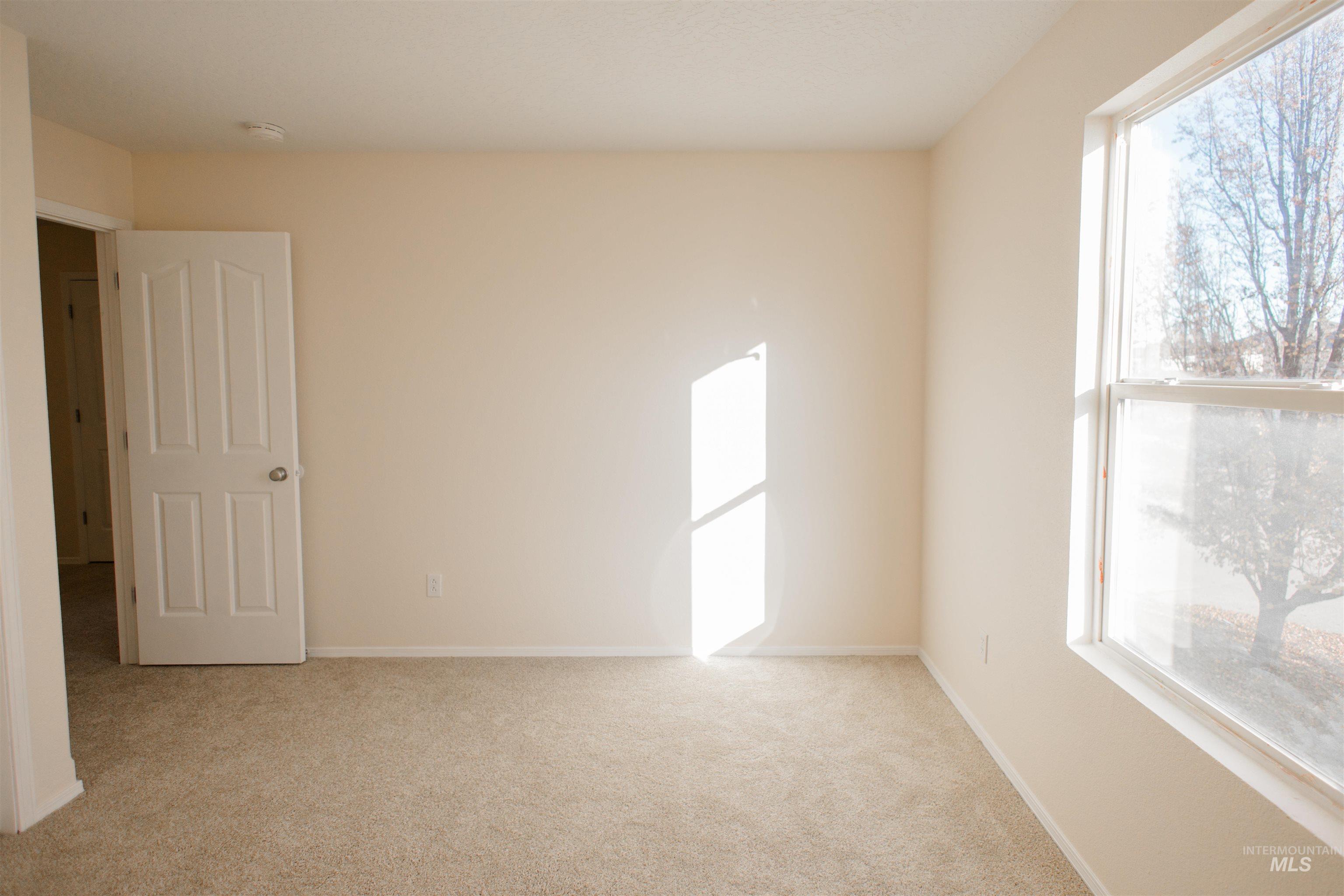 Empty room featuring light colored carpet and baseboards