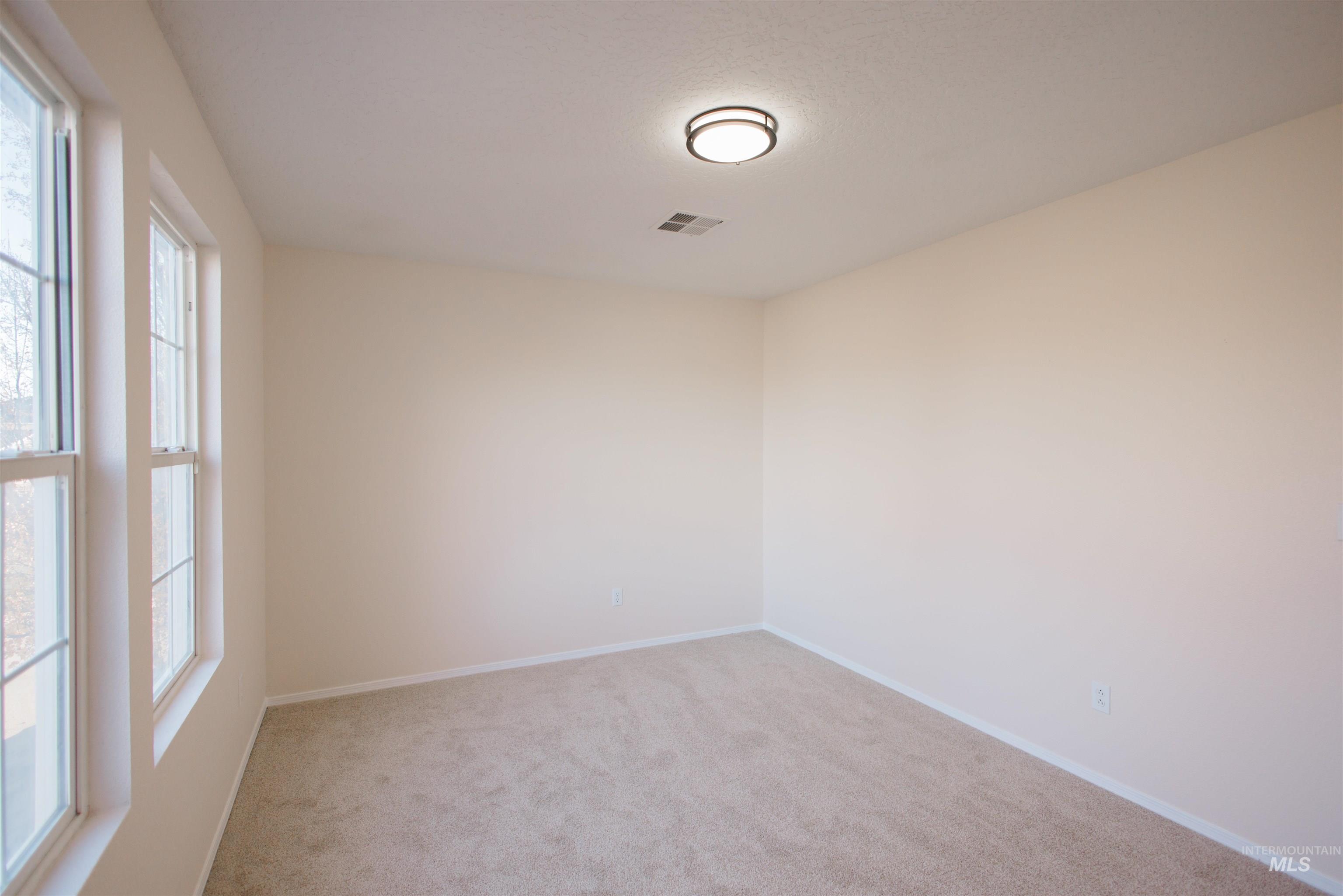 Empty room featuring light carpet and baseboards
