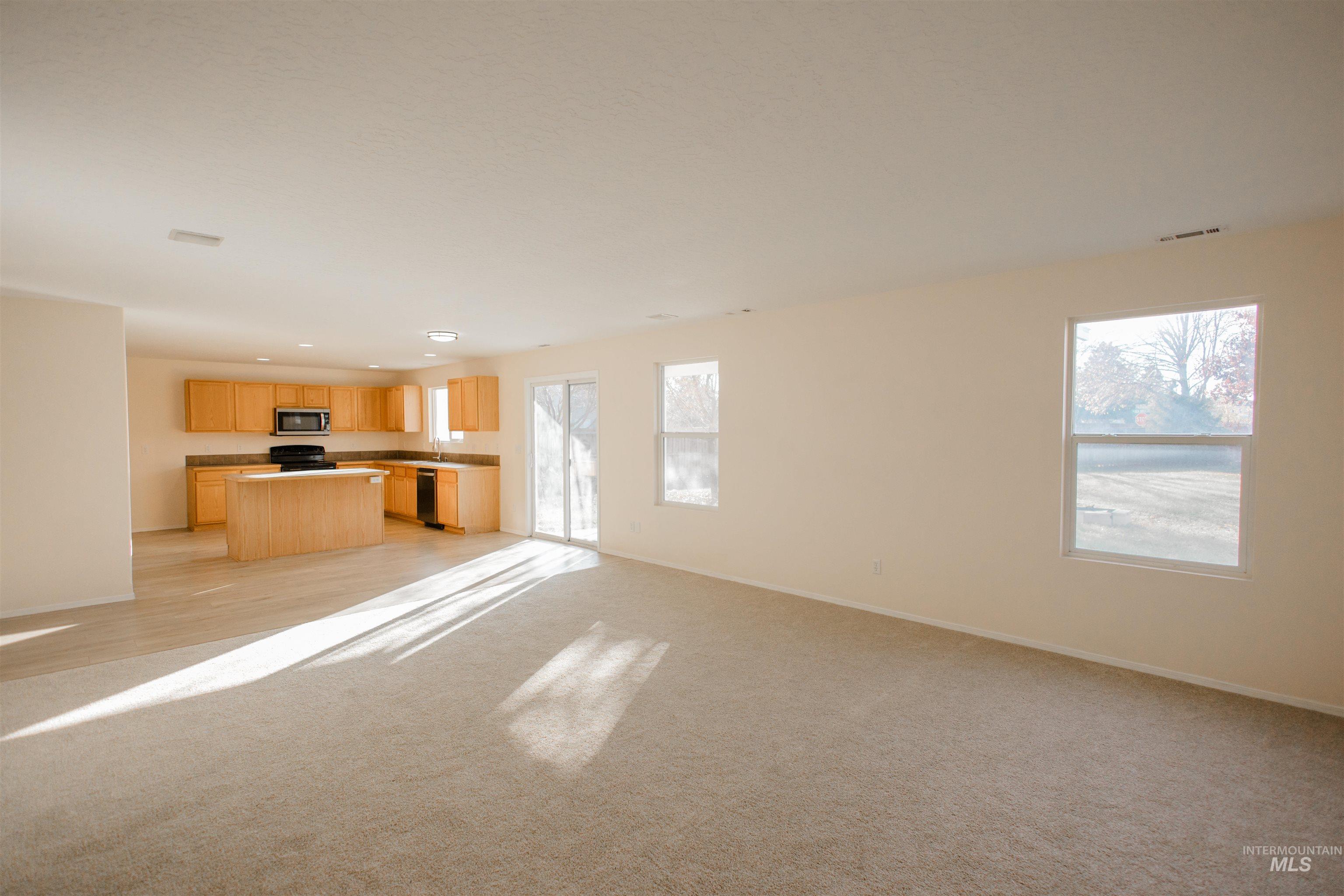 Unfurnished living room featuring light colored carpet and baseboards