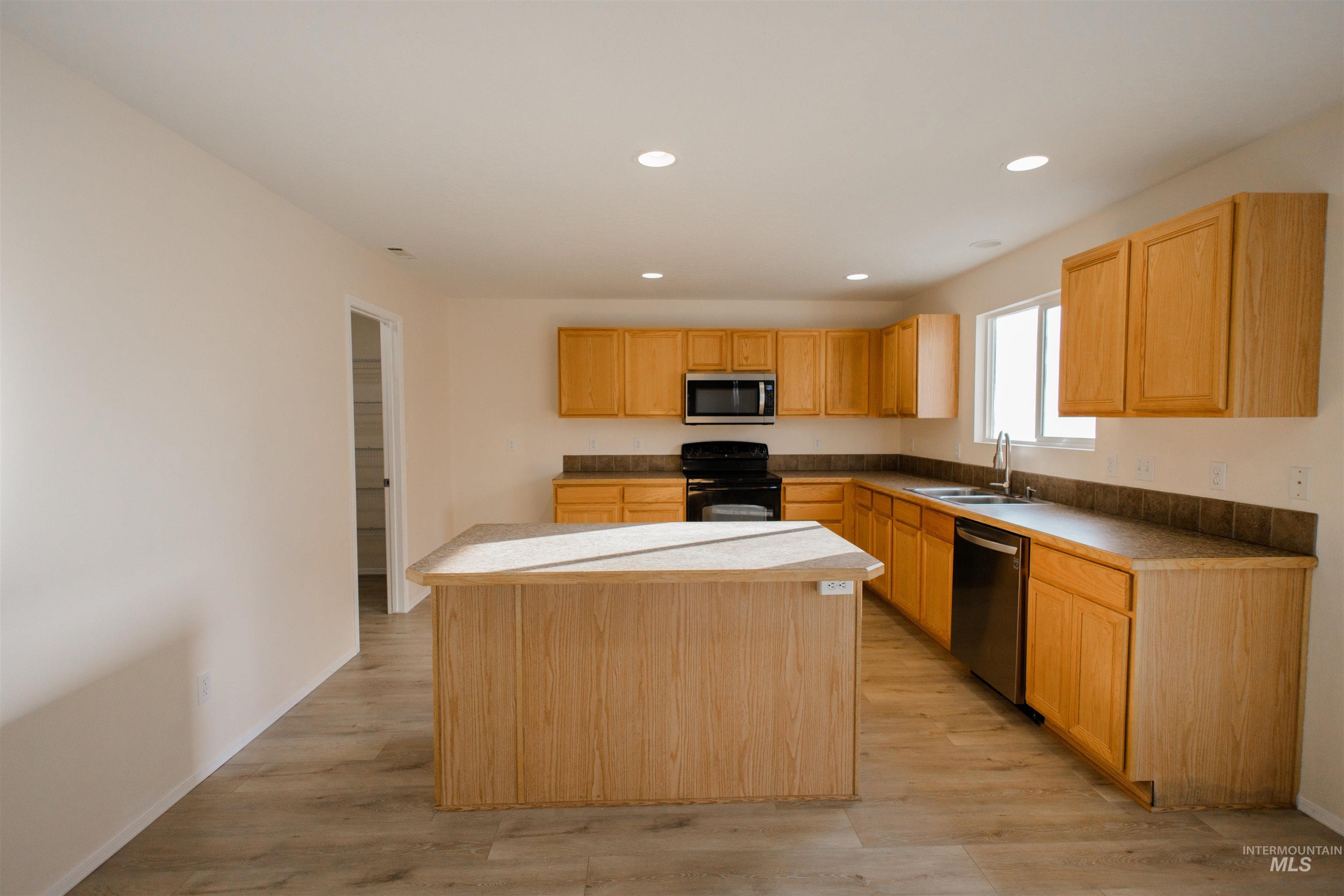 Kitchen with a center island, appliances with stainless steel finishes, light wood-style floors, recessed lighting, and light brown cabinetry