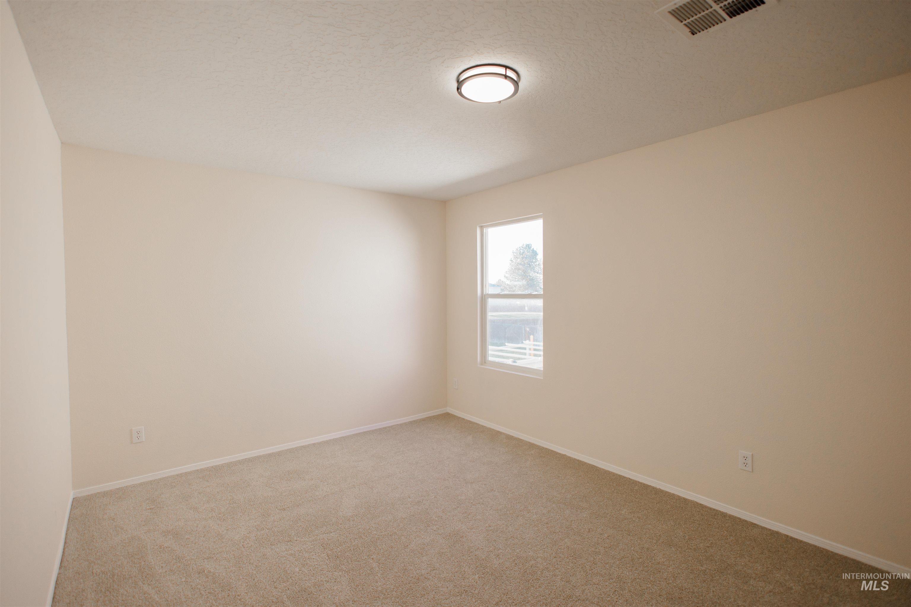 Unfurnished room featuring a textured ceiling and light colored carpet