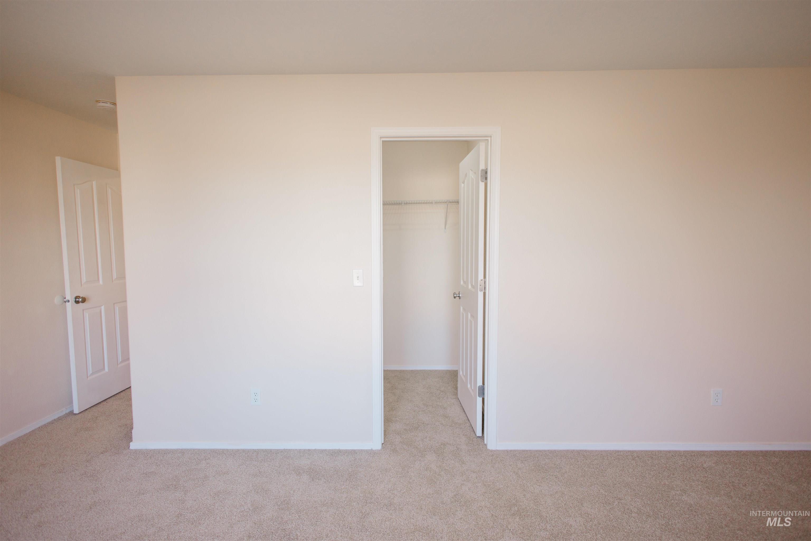 Unfurnished bedroom with a walk in closet and light carpet