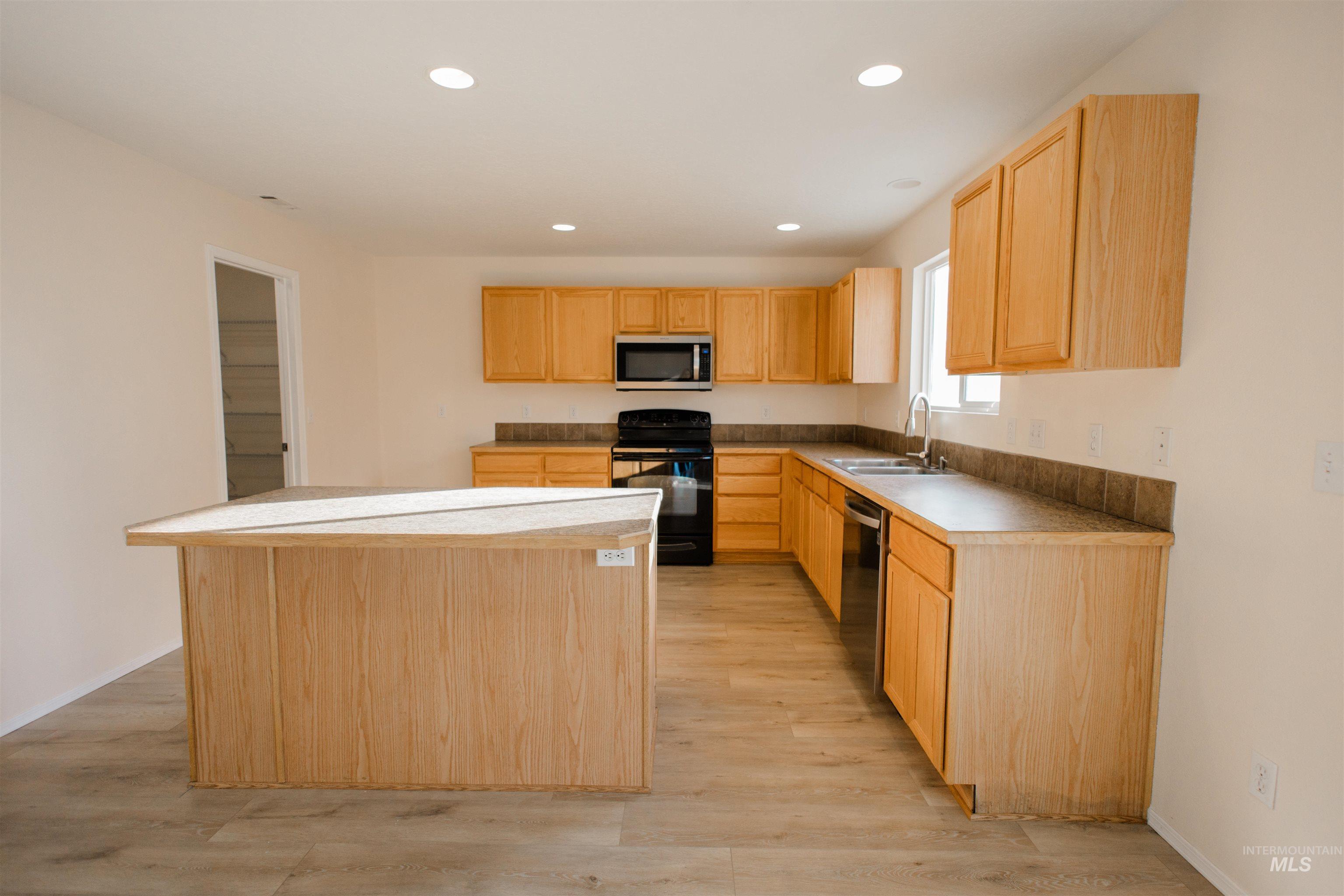Kitchen featuring a kitchen island, light brown cabinets, black range with electric cooktop, recessed lighting, and light wood-type flooring