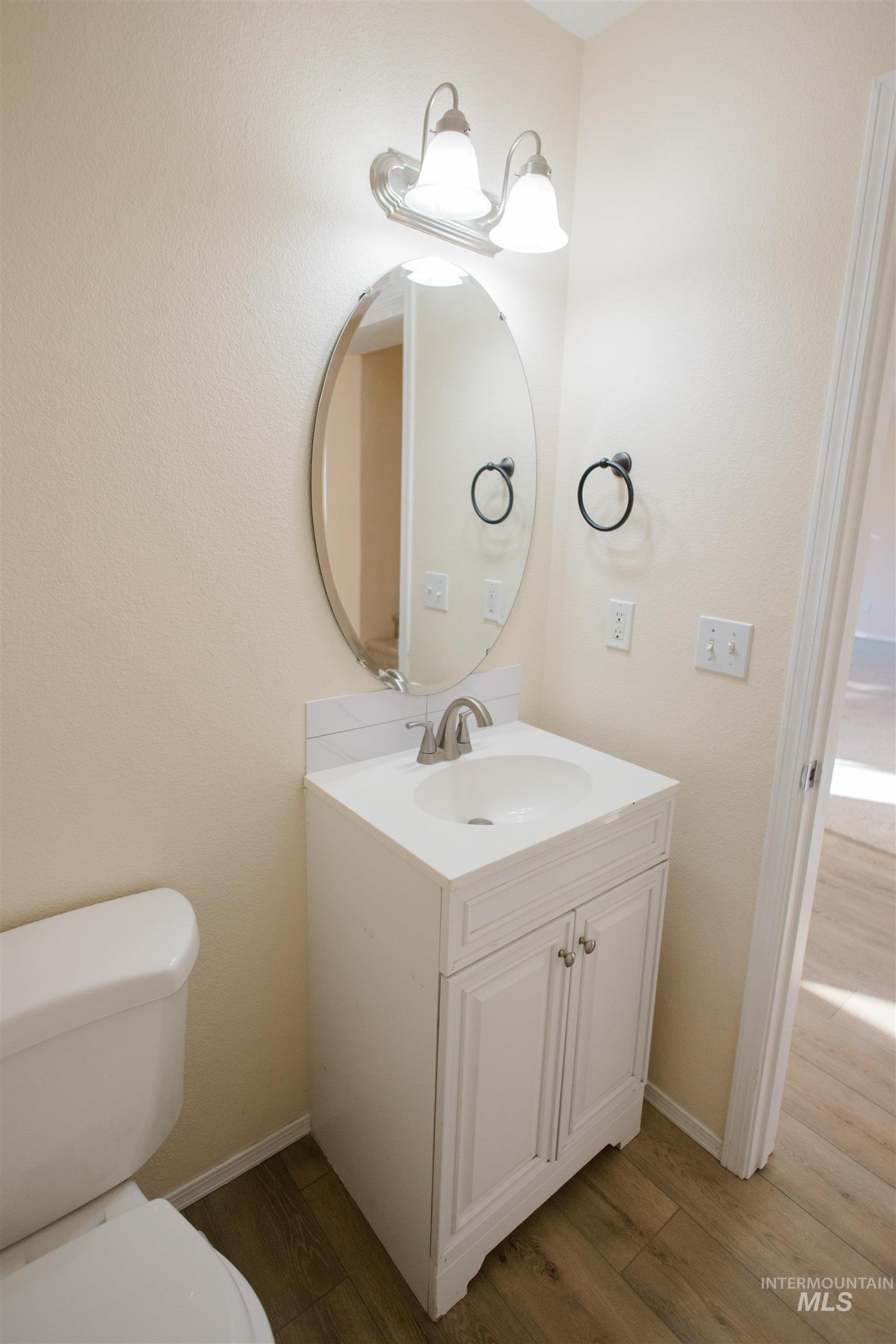Half bath with vanity, dark wood finished floors, and a textured wall