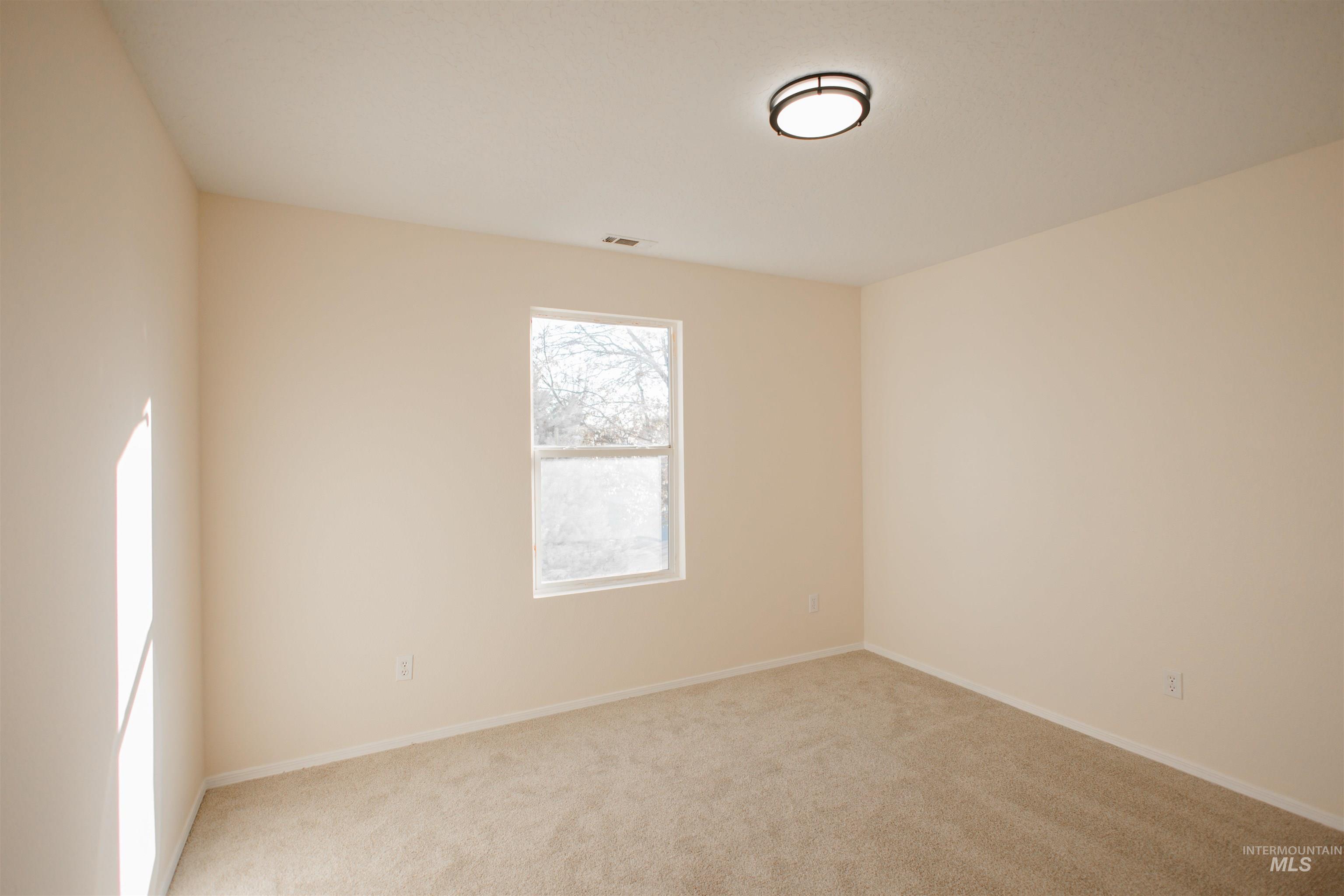 Spare room featuring light colored carpet and baseboards