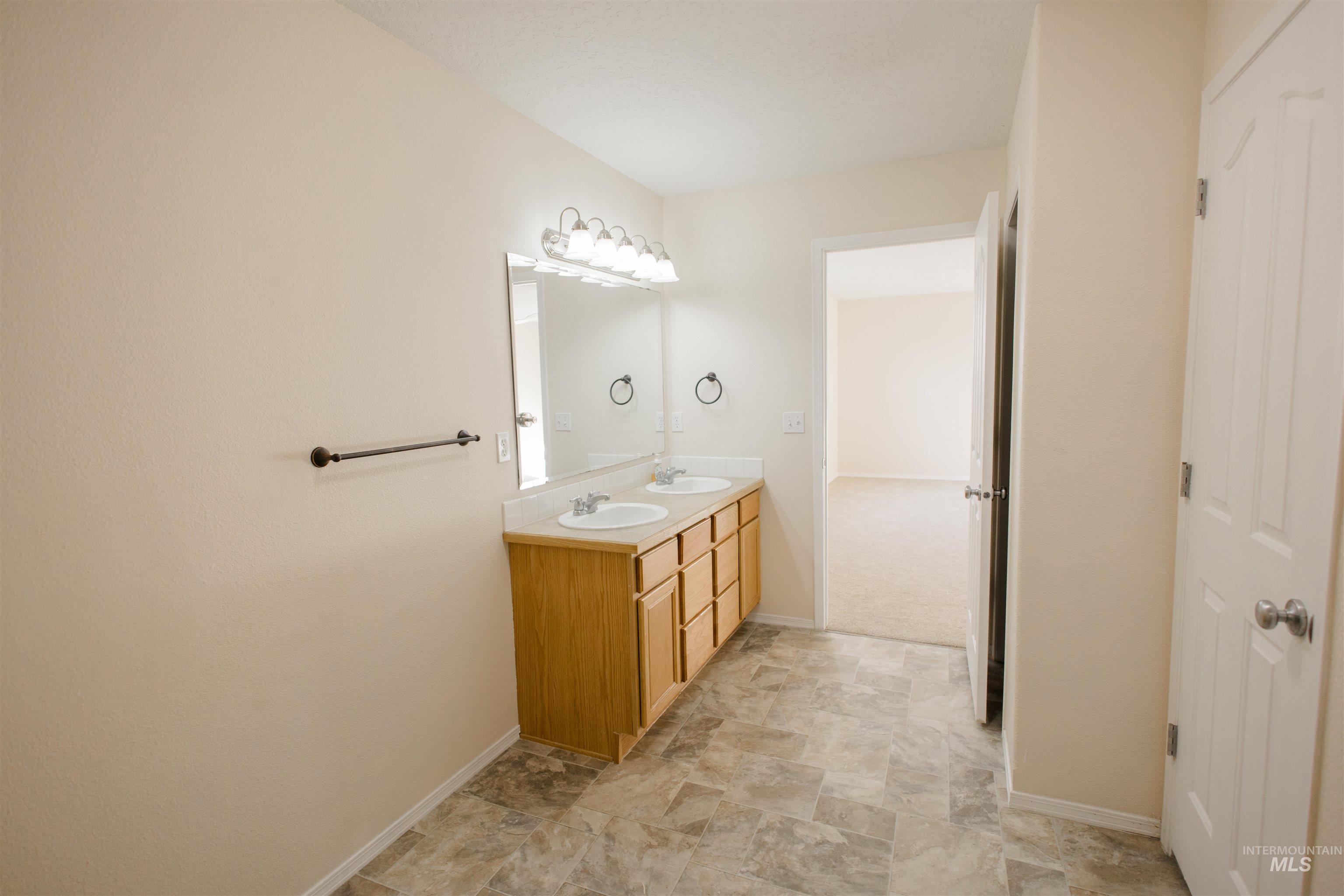 Bathroom with double vanity and stone finish floors