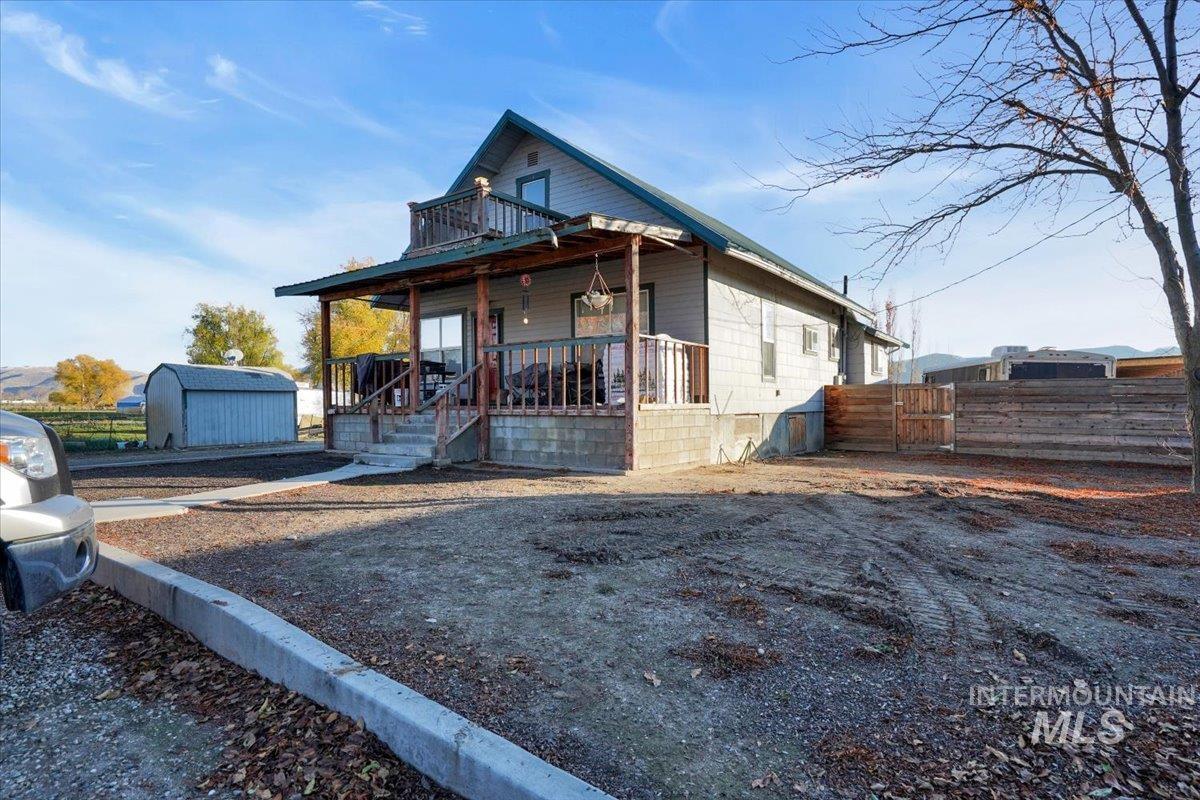 View of front of home featuring a porch, an outdoor structure, and a gate