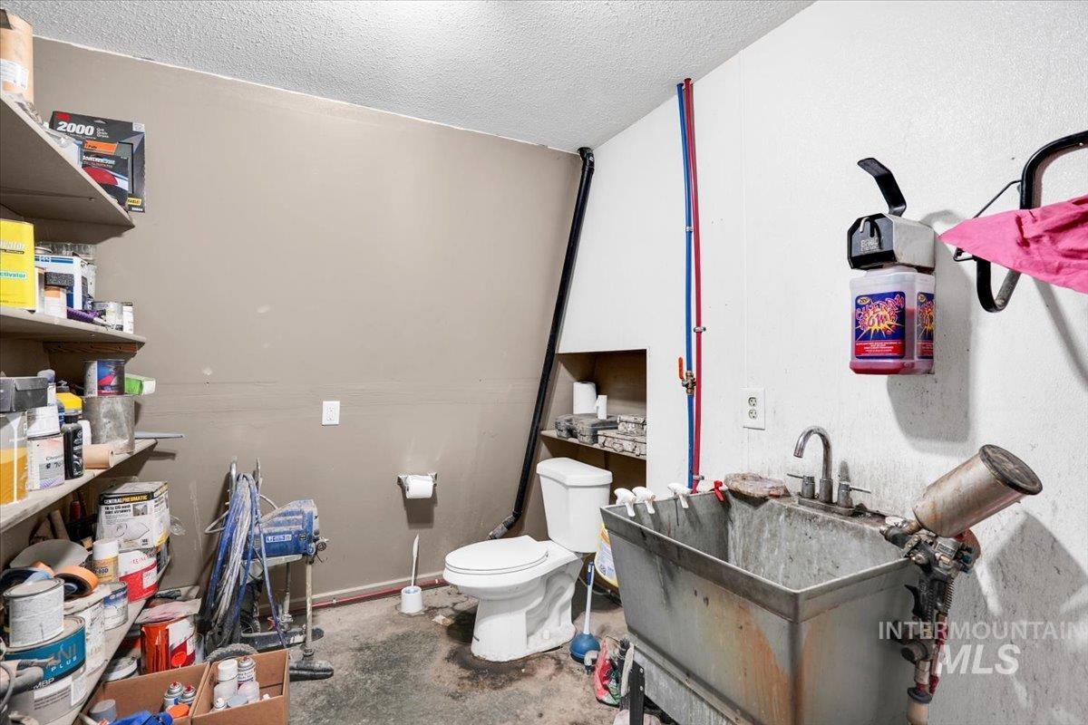 Bathroom featuring a textured ceiling, vanity, and concrete flooring