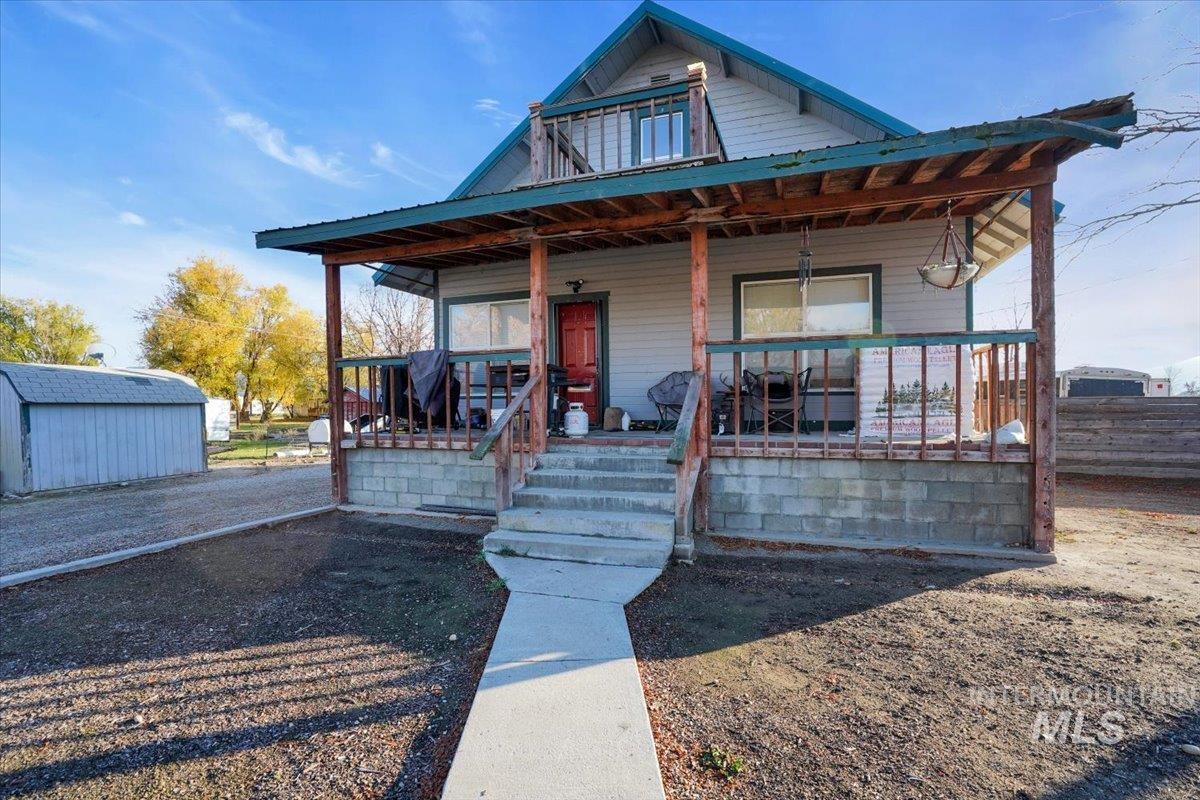 View of front of property featuring covered porch and an outbuilding