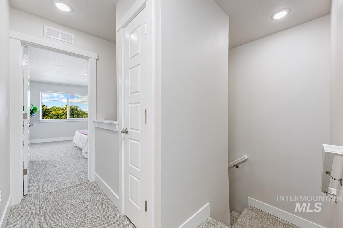 Corridor with light colored carpet, recessed lighting, and an upstairs landing