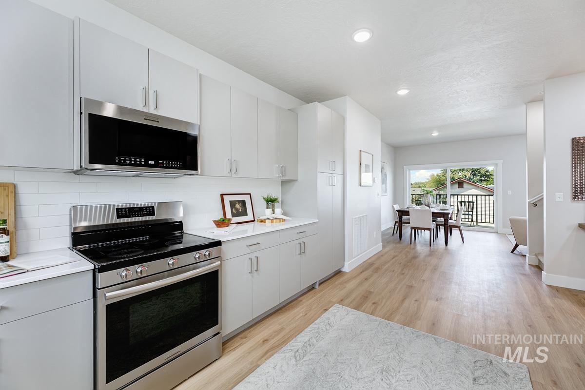 Kitchen featuring stainless steel appliances, light wood-type flooring, recessed lighting, decorative backsplash, and modern cabinets