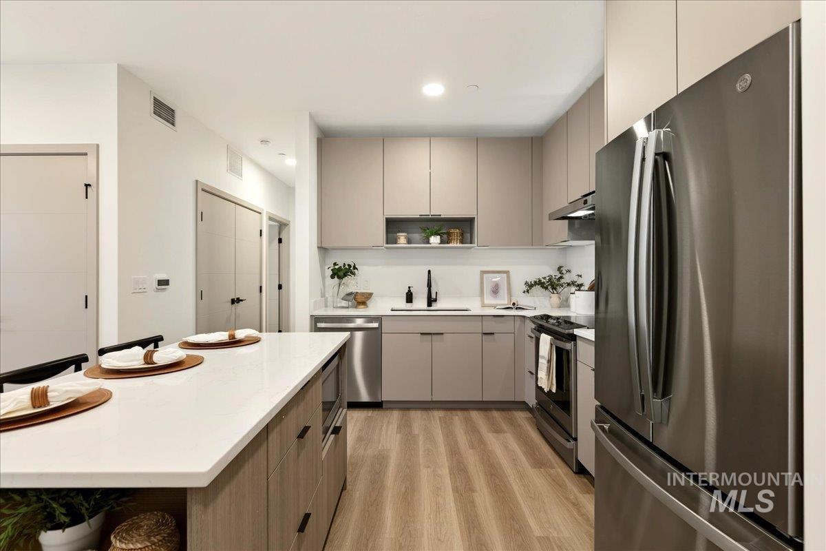 Kitchen featuring stainless steel appliances, open shelves, gray cabinetry, modern cabinets, and recessed lighting