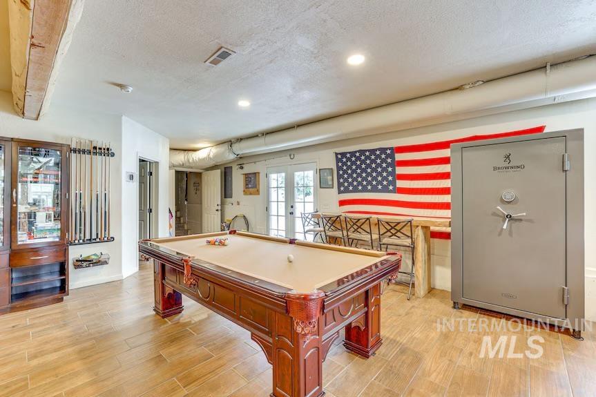 Recreation room with french doors, light wood-type flooring, pool table, a textured ceiling, and recessed lighting