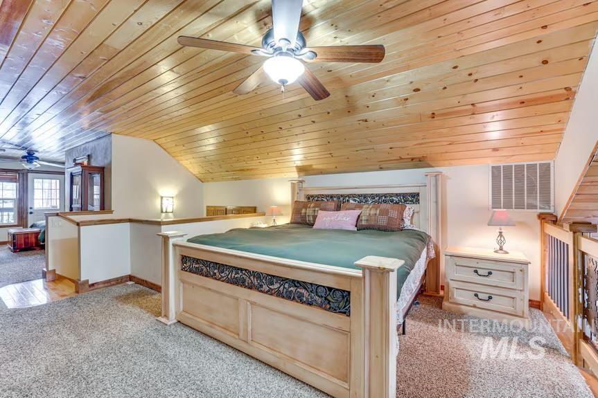 Bedroom with wooden ceiling, light carpet, and lofted ceiling
