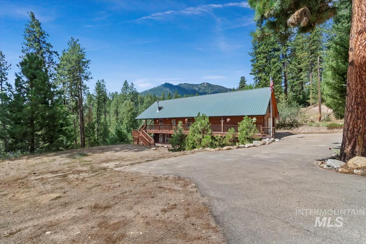 View of home's exterior with a metal roof, stairs, a deck with mountain view, and asphalt driveway