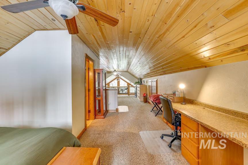 Office featuring lofted ceiling, wooden ceiling, carpet, a ceiling fan, and built in desk