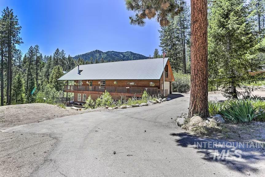 View of side of property featuring a mountain view, asphalt driveway, and a metal roof