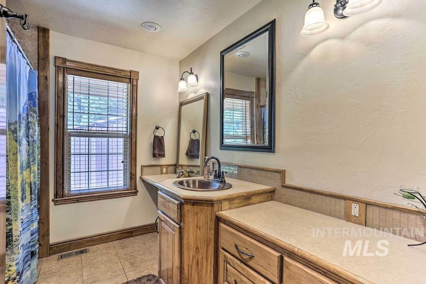 Bathroom with tile patterned flooring, vanity, and healthy amount of natural light
