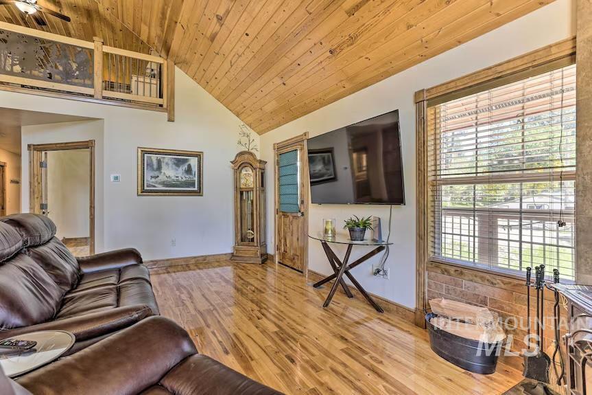 Living room with wooden ceiling, light wood finished floors, high vaulted ceiling, and a ceiling fan
