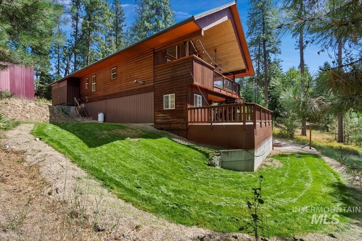 View of home's exterior with a yard, a balcony, and a wooden deck