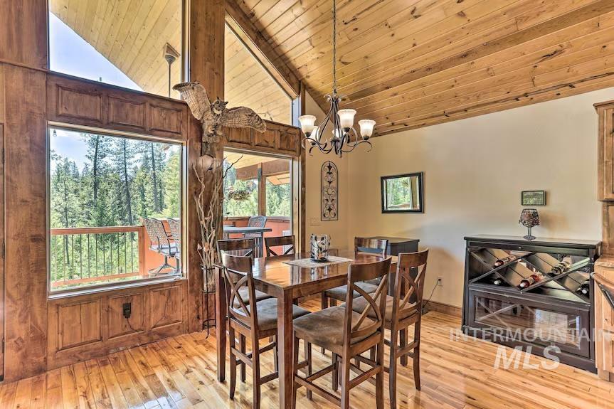 Dining space with lofted ceiling, wood ceiling, light wood finished floors, and a chandelier