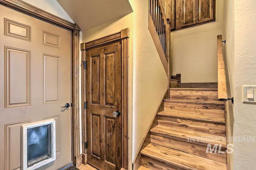 Stairs with a textured wall and lofted ceiling