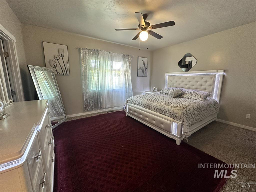 Bedroom featuring ceiling fan, carpet, and a textured ceiling