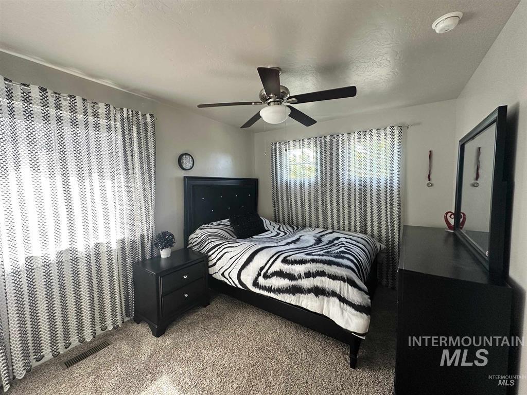 Carpeted bedroom featuring a textured ceiling and a ceiling fan