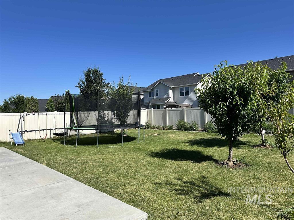 Fenced backyard featuring a trampoline