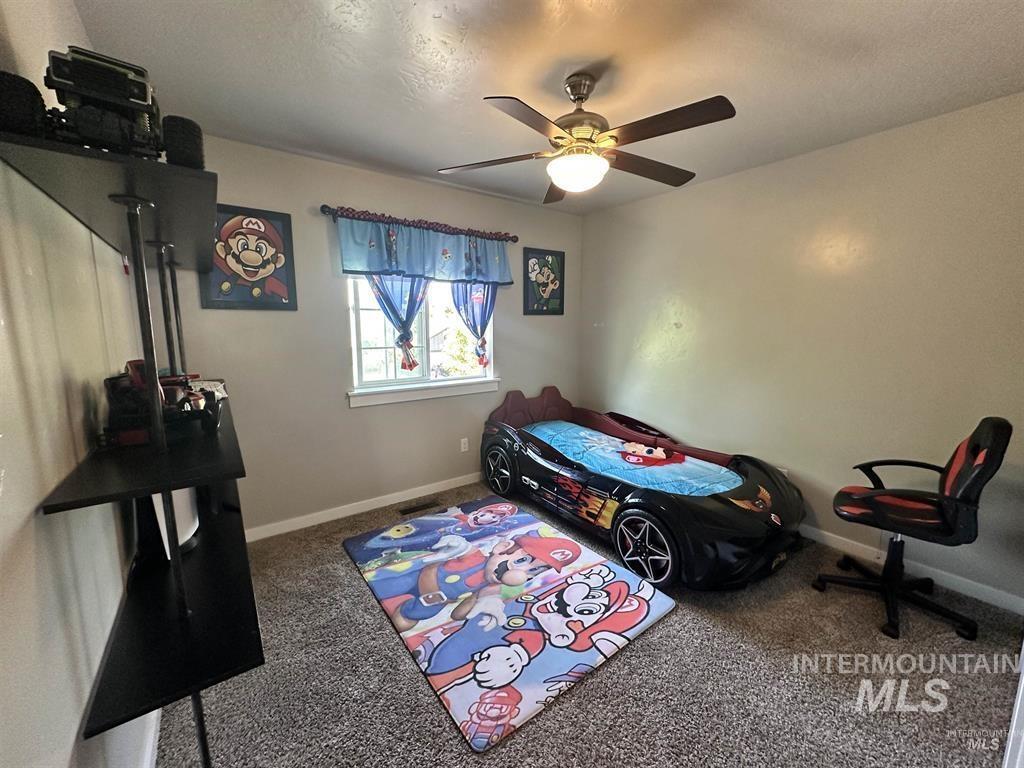 Bedroom featuring dark carpet, ceiling fan, and a textured ceiling