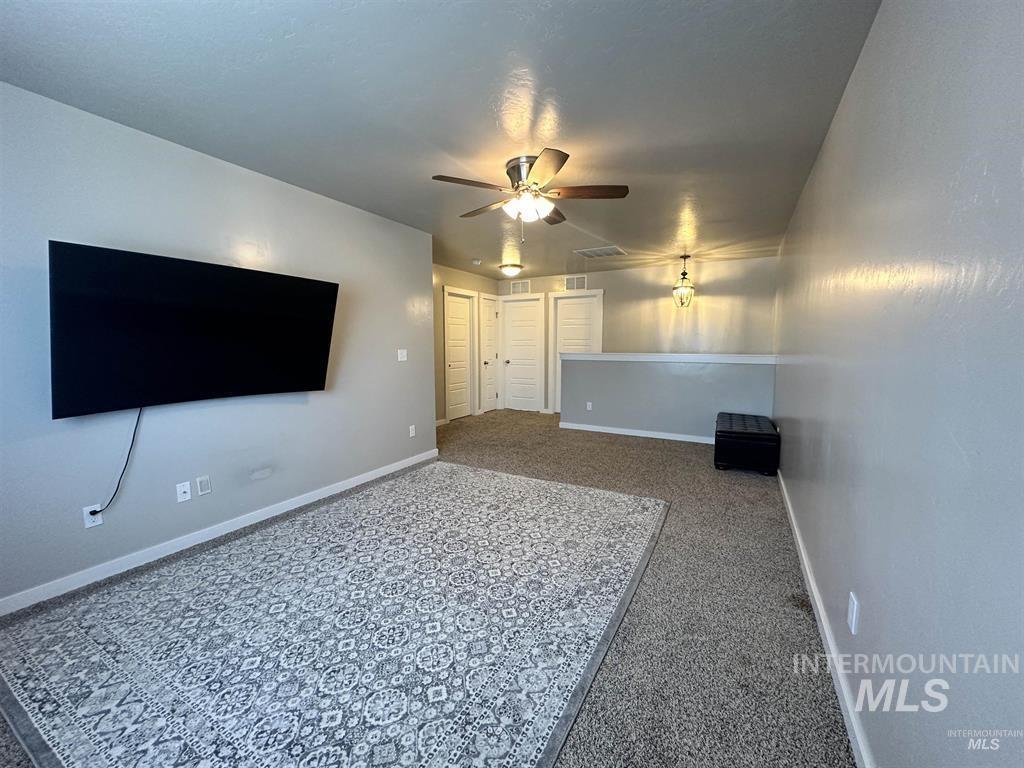 Unfurnished living room featuring baseboards and a ceiling fan