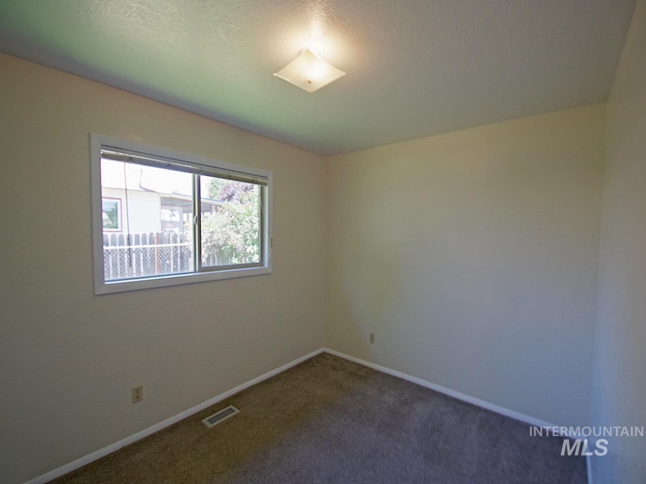 Carpeted room with a double-pane window and a flush-mount ceiling light fixture
