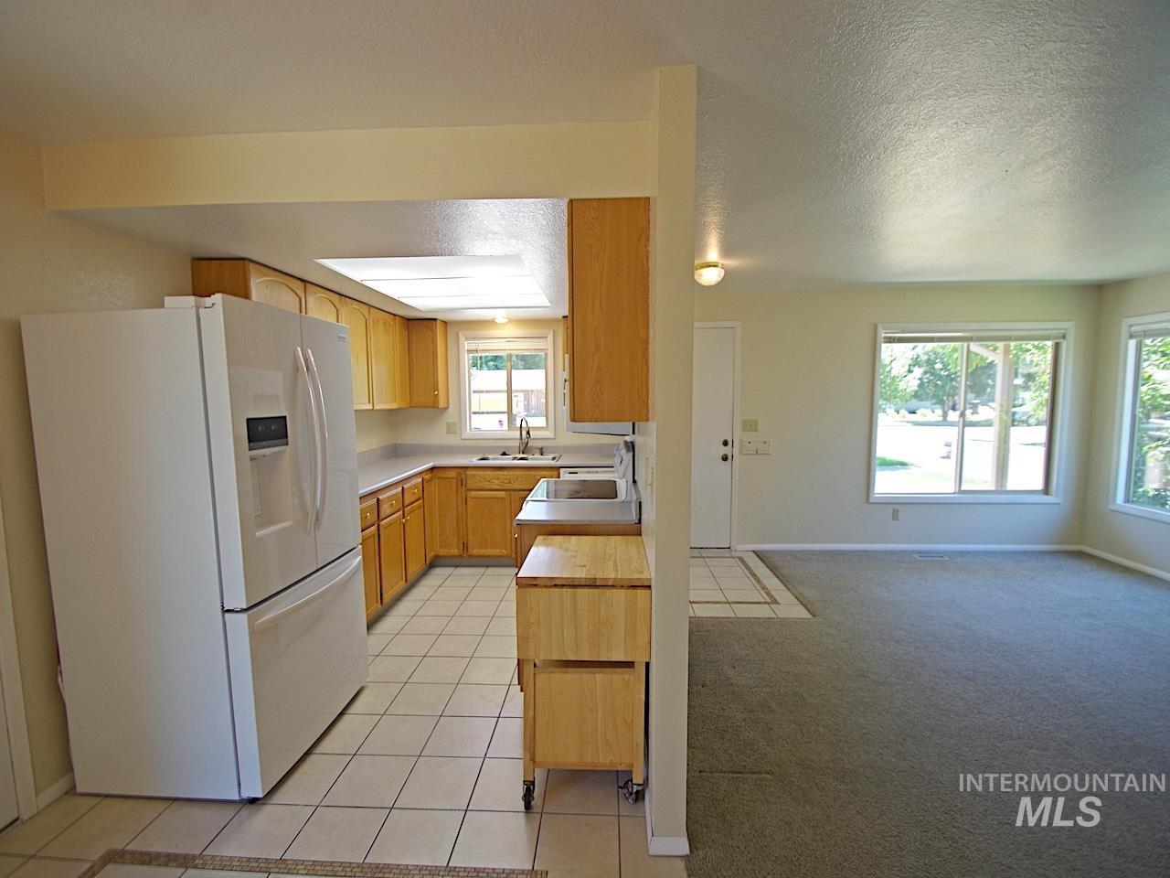 Kitchen featuring wood-finish cabinetry, white tiled flooring, and a recessed ceiling light