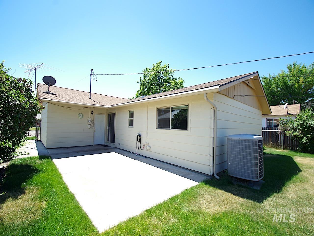 Rear exterior featuring a concrete patio, light-colored siding, and a brown shingle roof
