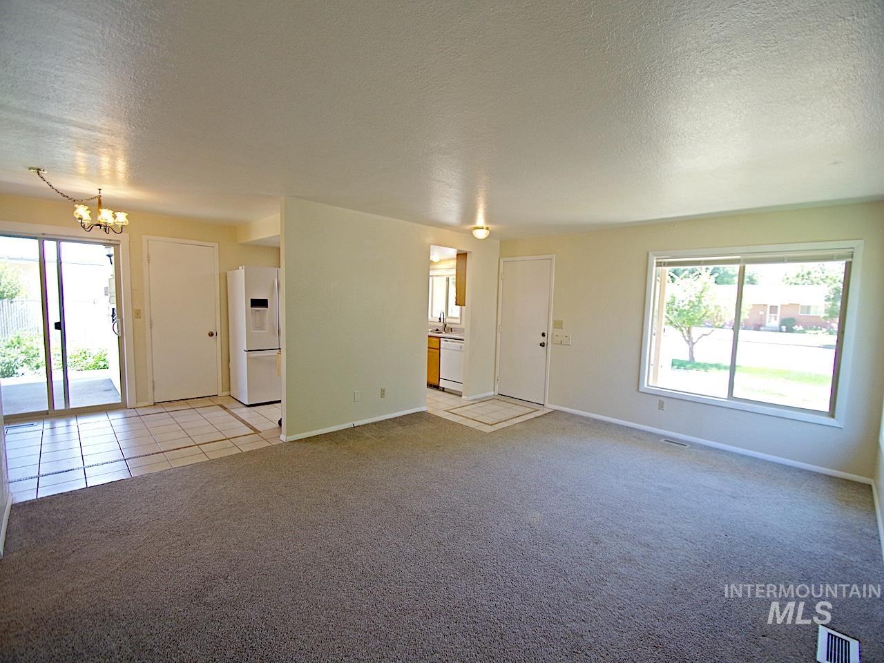 Living area featuring neutral-toned carpeting, a large window, and a white entry door