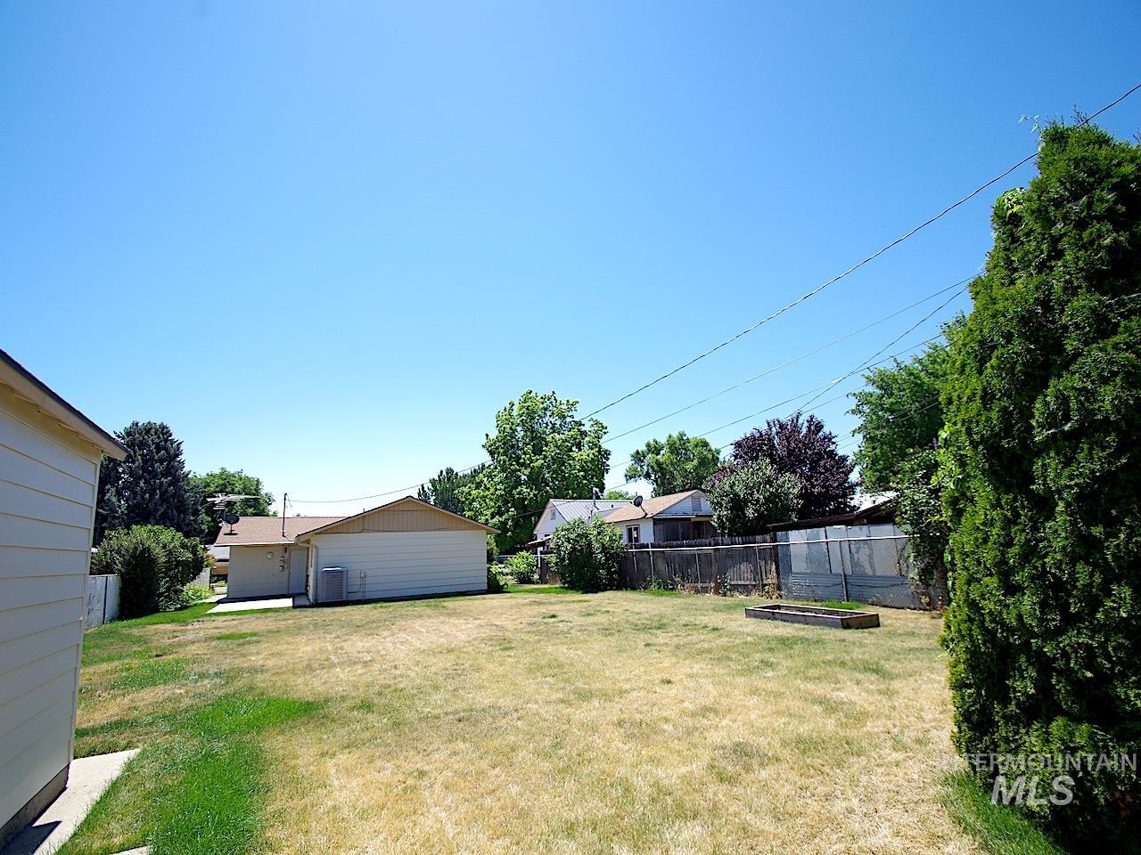 Expansive backyard featuring a fenced perimeter, established trees, and a raised garden bed