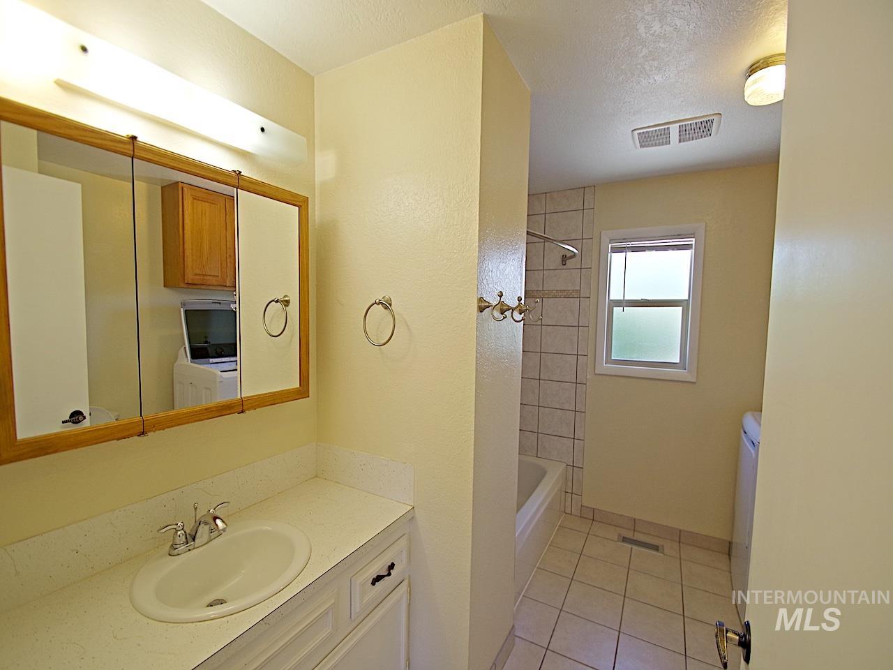 Bathroom vanity featuring an oval undermount sink with chrome fixtures, a wood-framed medicine cabinet with integrated lighting, and a white countertop