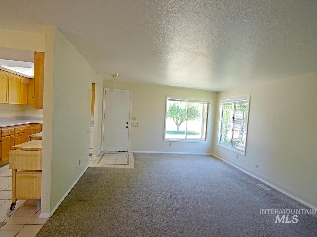 Carpeted living area featuring multiple windows providing natural light