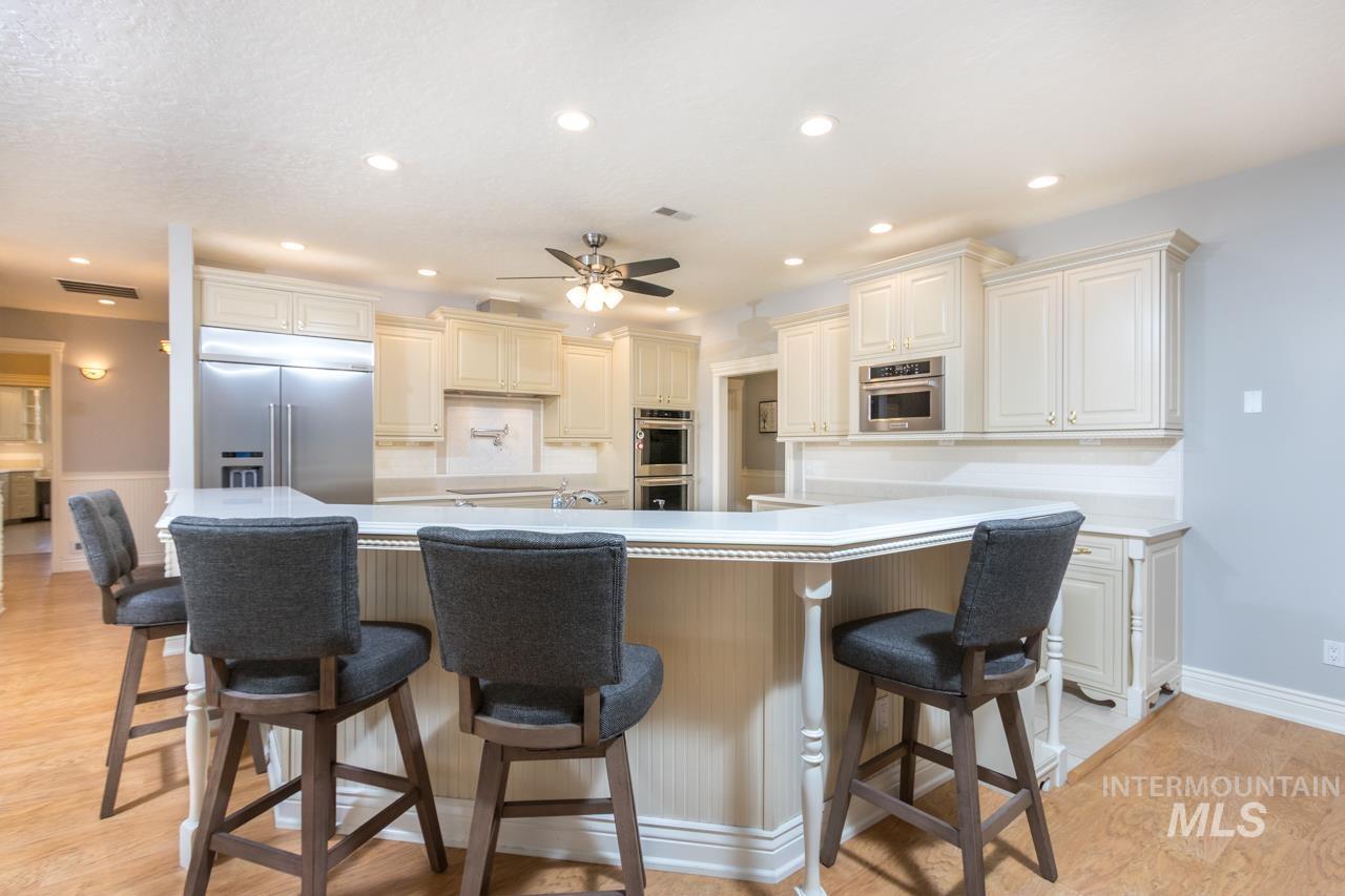 Kitchen with light wood-style floors, stainless steel appliances, a kitchen bar, light countertops, and recessed lighting