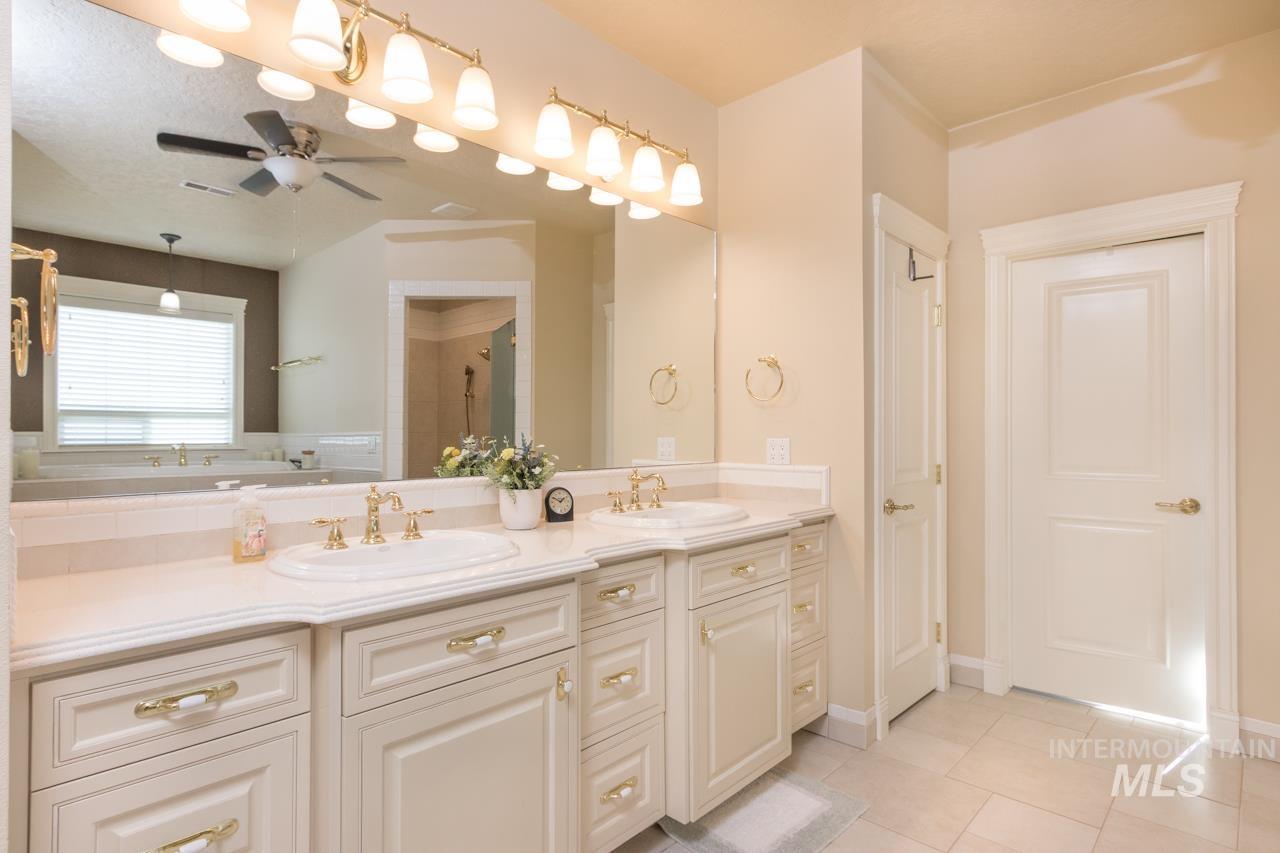 Full bathroom with double vanity, a stall shower, ceiling fan, and light tile patterned floors