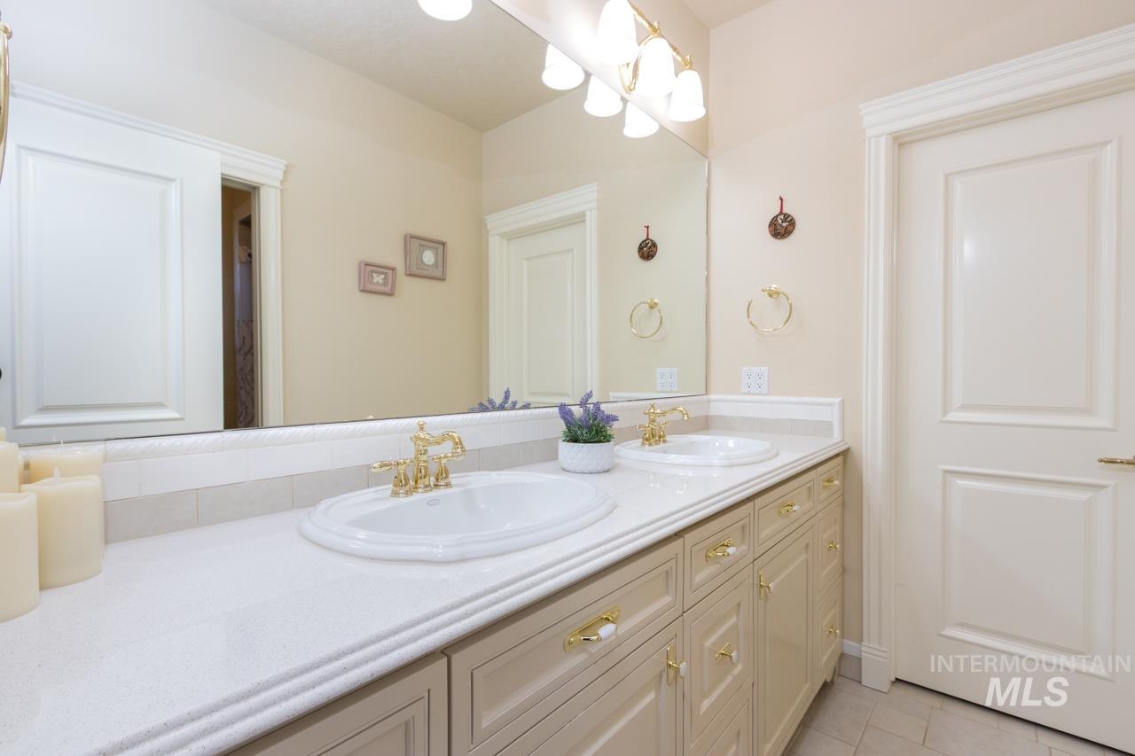 Full bathroom featuring double vanity, a chandelier, and light tile patterned flooring