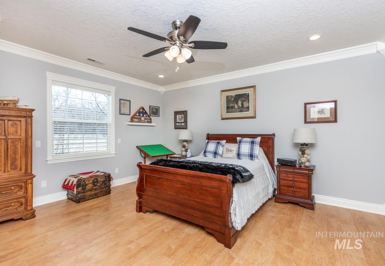 Bedroom with crown molding, light wood-style floors, a ceiling fan, a textured ceiling, and recessed lighting