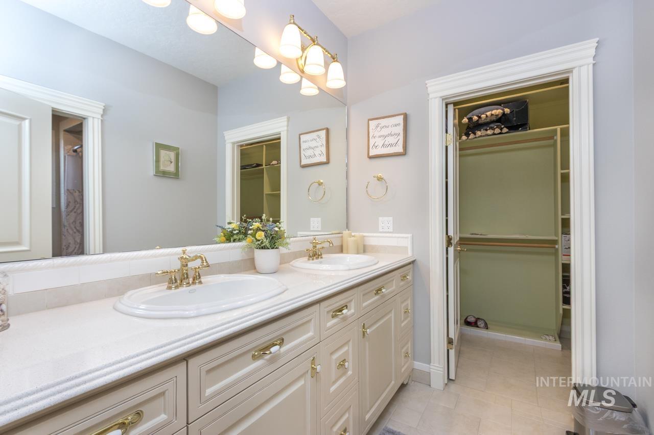 Bathroom with a walk in closet, double vanity, a shower with curtain, and light tile patterned floors