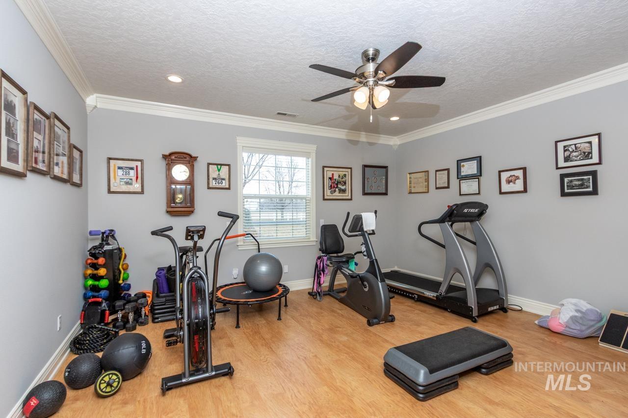 Workout area with crown molding, a textured ceiling, light wood finished floors, ceiling fan, and recessed lighting