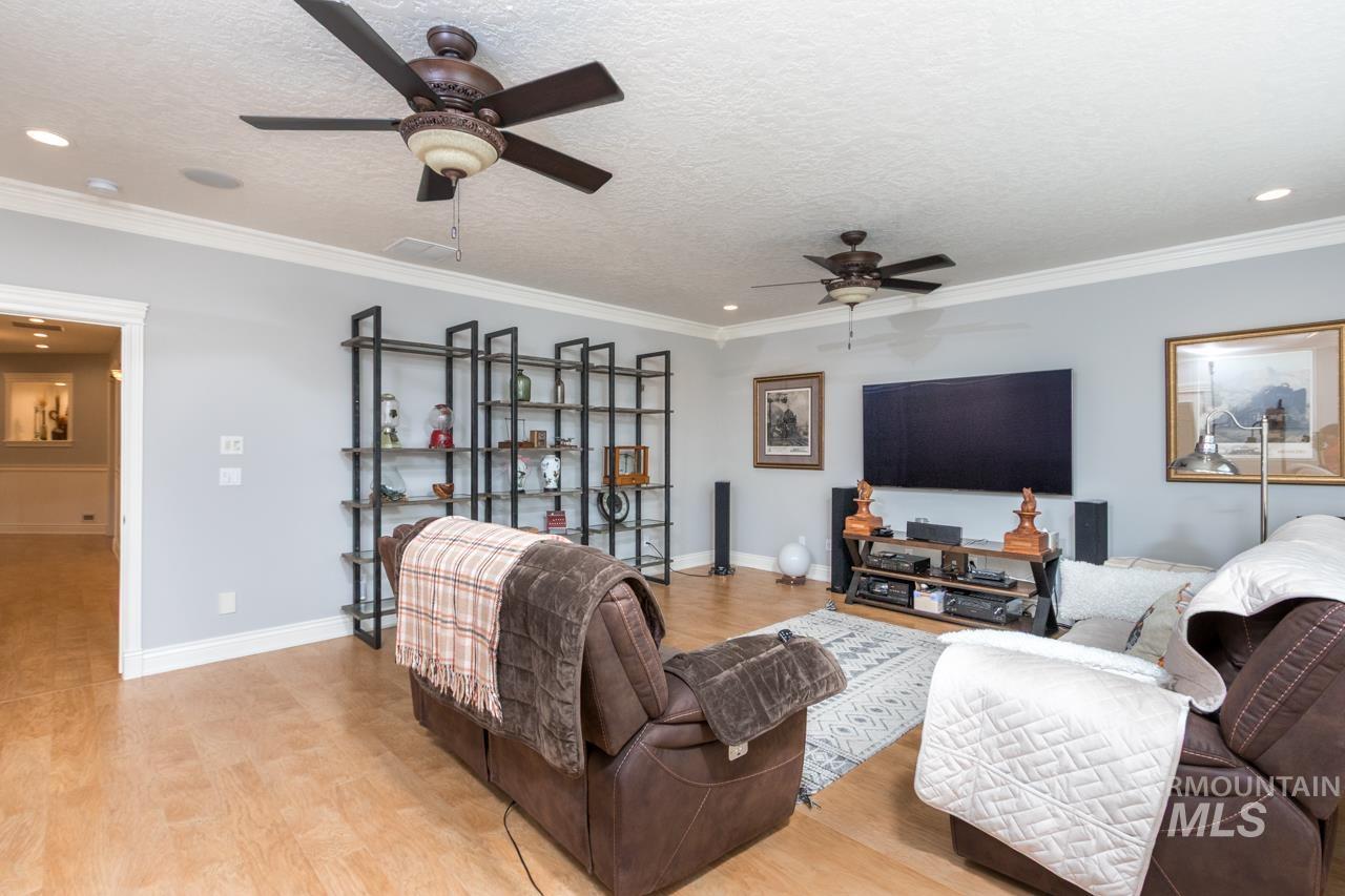 Living area featuring light wood-type flooring, a ceiling fan, a textured ceiling, crown molding, and recessed lighting