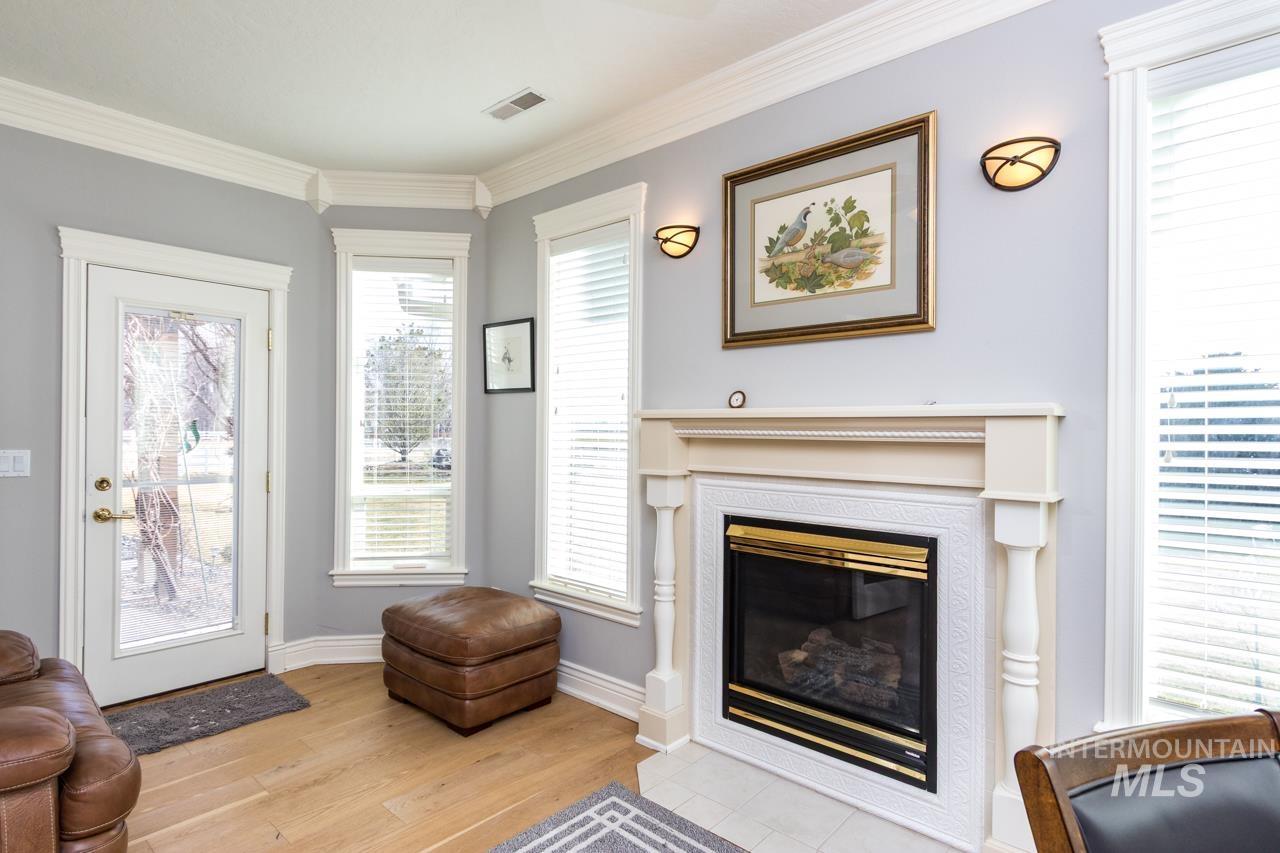 Living area featuring light wood-type flooring, crown molding, and a fireplace with flush hearth