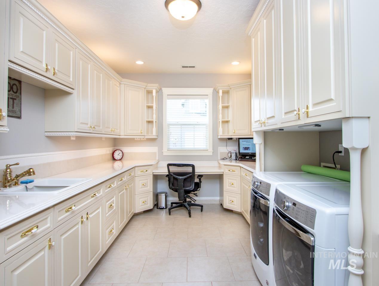 Laundry room featuring independent washer and dryer, cabinet space, light tile patterned floors, recessed lighting, and a desk