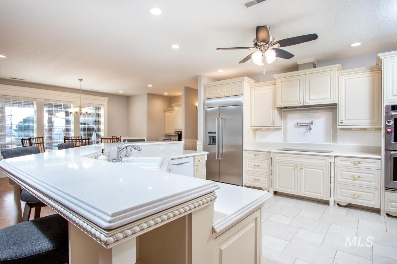 Kitchen featuring stainless steel appliances, cream cabinetry, a kitchen bar, a large island, and a ceiling fan